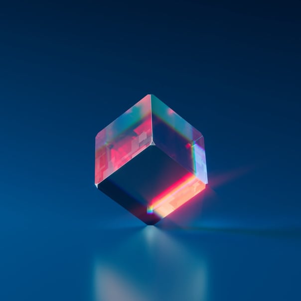 clear glass square-prism balancing on its vertex, while light passes through it and shows its reflection on the ground